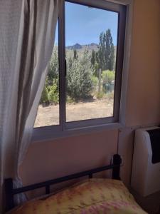 a bedroom with a window with a bed and a view at El Quillango in Villa Llanquin