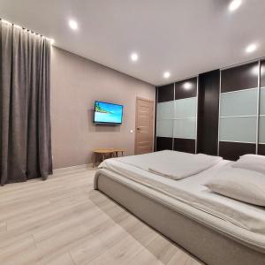 una camera da letto con un letto e una TV a parete di ApartPoltava Premium Relax двокімнатні апартаменти з ДЖАКУЗІ a Poltava