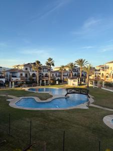 a swimming pool in a park with palm trees and buildings at Spectacular Flat Vera Playa in Playas de Vera