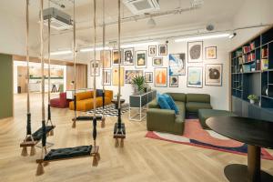 a living room with swings and paintings on the wall at Chiswick Parkside Apartments by Sleepy Lodge London in Kew Bridge
