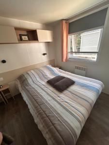 ein Schlafzimmer mit einem großen Bett mit Fenster in der Unterkunft Mobilhome Calme 6 Personnes Camping Pierre Couché in Saint-Brevin-les-Pins