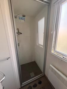 eine Dusche mit Glastür im Badezimmer in der Unterkunft Mobilhome Calme 6 Personnes Camping Pierre Couché in Saint-Brevin-les-Pins + 14 Fotos