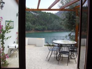 eine Terrasse mit einem Tisch, Stühlen und einem See in der Unterkunft Riverside House in Dornes