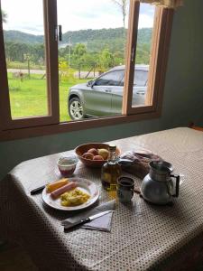 einen Tisch mit einem Teller Essen und einem Fenster in der Unterkunft Casa de Campo, Pet friendly em Campo Alegre-SC in Campo Alegre