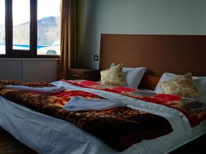 a bed with a blanket and pillows on it at pangong rainbow cottage in Lukung