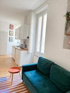 a living room with a blue couch and a kitchen at Mourillon proche plages in Toulon