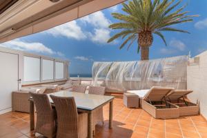 a patio with a table and chairs and a palm tree at Confortable Bungalow With Views in San Bartolomé de Tirajana
