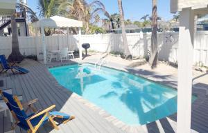 a swimming pool with two chairs and an umbrella at Bungalow Beach Resort in Bradenton Beach