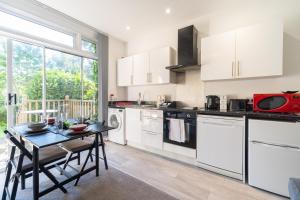une cuisine avec des placards blancs et une petite table avec une table dans l'établissement RUBY Delightful Suite Moseley Mews, Birmingham By STAE-Homes, à Birmingham