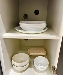 a white shelf with plates and bowls on it at Moderno apto - vista maravilhosa in Londrina