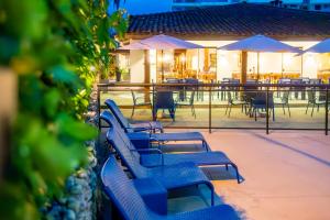 a row of blue benches on a patio with tables and umbrellas at Mar e Praia Hotel in Ubatuba