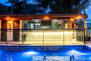 a house with a swimming pool at night at Mar e Praia Hotel in Ubatuba