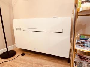 a white refrigerator in a corner of a room at Le Tailleur, centre historique, fibre, climatisation, ESS, rez-de-chaussée, BedinShop in Romans-sur-Isère