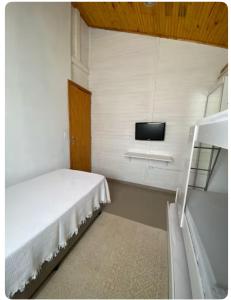 a small bedroom with a bed and a tv at Chalé em torno da Mata Atlantica in Itu