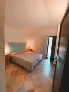a bedroom with a bed and a lamp on a tiled floor at La Turritta in Badesi +17 photos