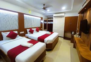 a hotel room with two beds and a flat screen tv at Hotel Jeyam in Kanyakumari