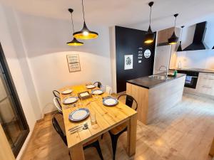 a dining room with a wooden table and a kitchen at Apartamento Vive Zaragoza in Zaragoza