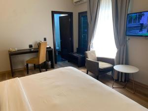 a bedroom with a bed and a desk and a tv at The Sojourner By Genesis in Ikeja