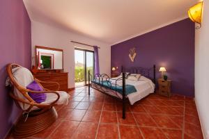 1 dormitorio con paredes moradas, 1 cama y 1 silla en Monte Holiday House, en Luz