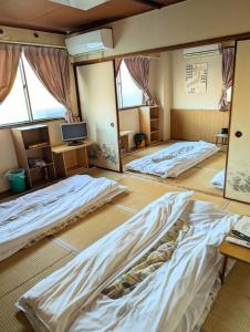 a room with three beds in it with a tv at ビジネスホテルみやこ in Higashi-osaka