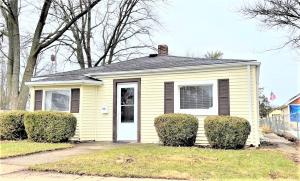 a yellow house with a white door and some bushes at High - Family Neighborhood, Pet Friendly in Van Wert