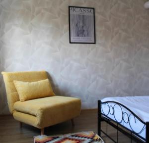 a bedroom with a yellow chair and a bed at AP Apartment's Rodzinny in Wałbrzych