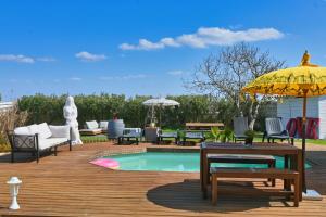 a wooden deck with a pool and a yellow umbrella at La Maison du Bonheur, Piscine, Jacuzzi, Billard in Le Grau-du-Roi
