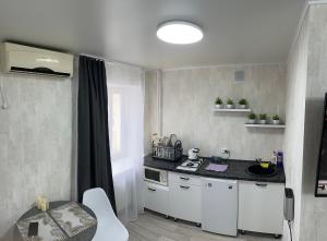 a kitchen with white cabinets and a black counter top at Центр Гоголя 78 in Kostanay