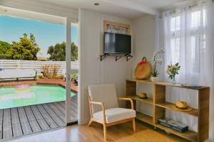 a living room with a tv and a chair and a pool at La Maison du Bonheur, Piscine, Jacuzzi, Billard in Le Grau-du-Roi
