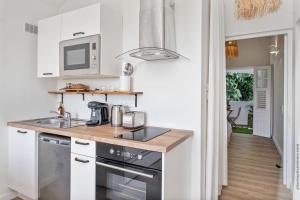 a kitchen with white cabinets and a sink and a microwave at Le cocon Aimée in Fort-de-France