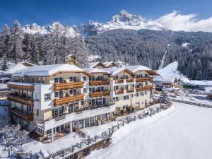 ein Hotel im Schnee mit Bergen im Hintergrund in der Unterkunft Familienhotel Maria in Obereggen