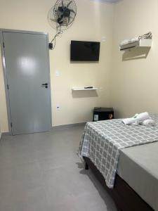 a bedroom with a bed and a door with a fan at Pousada Santa Rita in Roseira