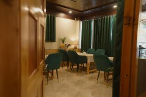 a dining room with a table and green chairs at Hotel Mid Orchard Kasol -River Side in Kasol +77 photos