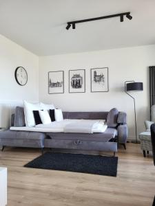 a living room with a couch and a clock on the wall at Apartament 150 Zaspa VVita z ogrodem i tarasem in Gdańsk +44 photos