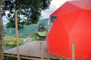 a red house on a wooden deck with a swing at Ecobindu-Domo in Albán