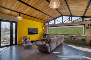 a living room with a couch and chairs and a tv at Tuscan Cozy Escape with View, Garden & Breakfast in CastellʼAzzara