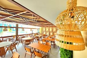 a restaurant with tables and chairs and a chandelier at Flat Luxo Alto Padrão, Praia de Muro Alto, Makia Beach Experience in Ipojuca