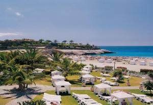 a beach with white umbrellas and chairs and the ocean at 5-bedroom Villa in Playa del Duque in Adeje