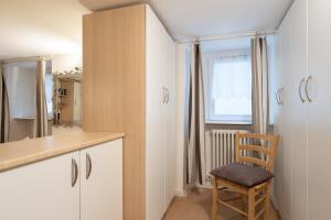 eine Küche mit weißen Schränken und einem Holzstuhl in der Unterkunft Bellano Studio 2 in Bellano
