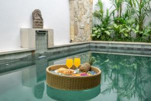 a basket of food and two glasses of orange juice at Exquisite 3-Bedroom Villa in Seminyak with Private Rooftop Oasis in Kerobokan