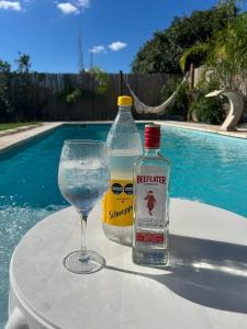 a bottle and a glass on a table near a pool at La Merced Areco in San Antonio de Areco