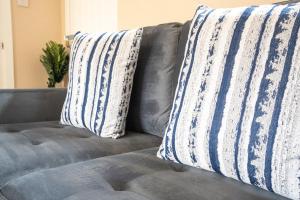 a gray couch with two pillows on it at 2 BDR House By Caledonia Luxe Stays Short Lets & Serviced Accommodation Bathgate in Bathgate
