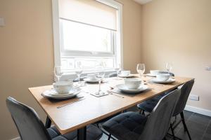 a dining room table with chairs and a large window at Marina House in Bathgate