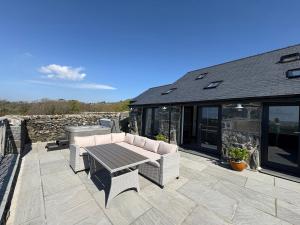 a patio with couches and a table and a stone wall at Gaerau Bach in Llanbedr