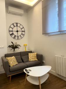 Una sala de estar con un sofá y un reloj en la pared. en Retiro Home, en Madrid