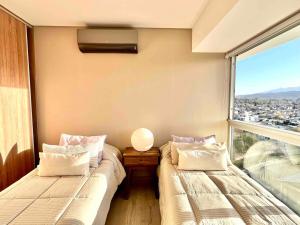 deux lits dans une chambre avec une grande fenêtre dans l'établissement Departamento de lujo en el corazón de Mendoza, à Villa Marini
