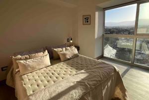 une chambre avec un grand lit avec une grande fenêtre dans l'établissement Departamento de lujo en el corazón de Mendoza, à Villa Marini