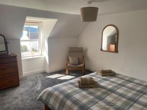 a bedroom with a bed and a chair and a mirror at The old Farmhouse Minutes from lochness in Drumnadrochit