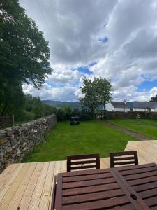 a wooden table and two chairs on a wooden deck at The old Farmhouse Minutes from lochness in Drumnadrochit