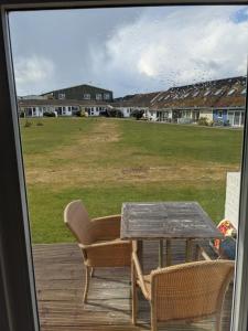 a table and chairs on a porch with a view of a field at Saltbox B4 holiday cottage in Freshwater
